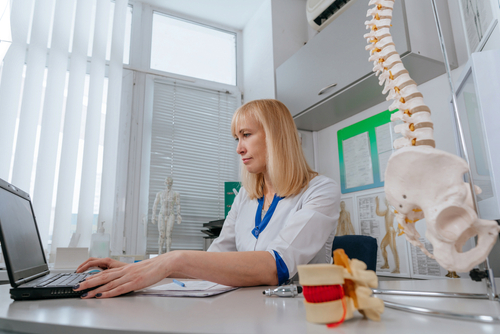 Chiropractor in clinic using laptop