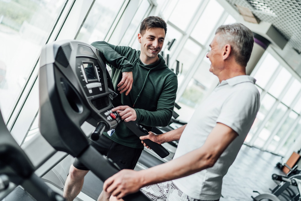 Personal trainer in gym with client on treadmill