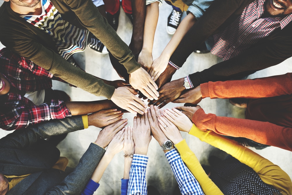 Diverse group of people placing hands together