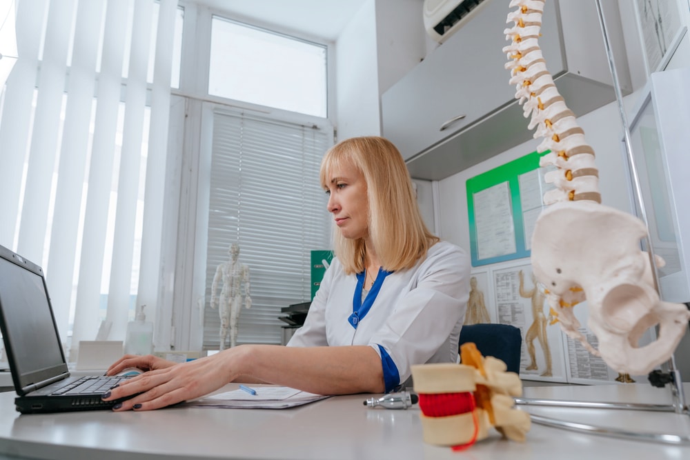 Physical therapist using laptop in clinic