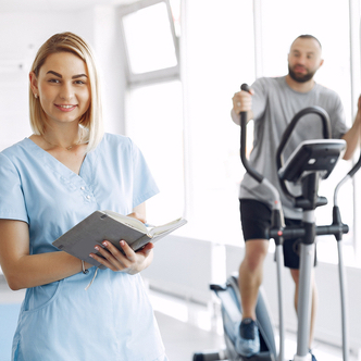 Female physiotherapist with male patient on cross trainer.